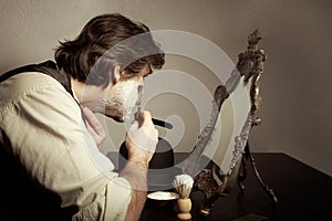 Shaving of man`s face in prewar style with razor and brush photo