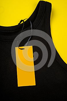 Price tag hang over black t-shirt on  yellow background - Image