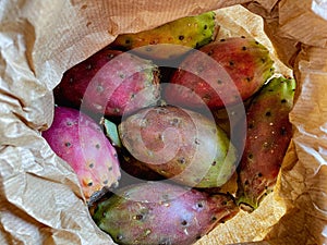 Prickly pear cactus colorful fresh ripe whole and cut fruits in brown paper bag.