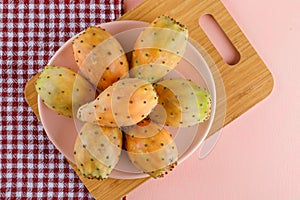 Prickly pears in a plate with cutting board flat lay on pink and picnic cloth background