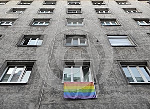 Pride month rainbow colored flag hanging from a window in the street