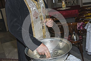 The priest assistant filled Christening Baptismal Font with Holy Water at the church during the ceremony