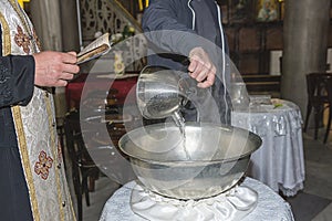 The priest blesses Christening Baptismal Font filled with Holy Water at the church during the ceremony