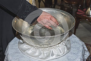 The priest blesses Christening Baptismal Font filled with Holy Water at the church during the ceremony