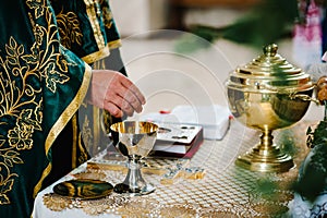 The priest blesses cup. the Bible, cross on table. Priest during a wedding ceremony. Priest celebrate a mass at the church.