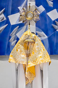 Priest blessing with altar sacrament, golden Ostensory or Monstrance for worship at Catholic church ceremony
