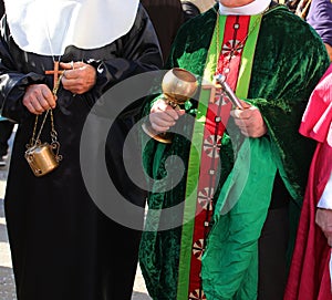 priest with cassock and aspergillum with holy water and incense during the holy mass
