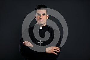 Priest in cassock with cross on black background