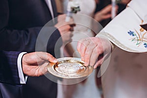 Priest golding golden wedding rings on plate in church at wedding matrimony. traditional religious wedding ceremony