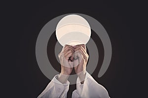 Priest hands lifting a communion bread photo