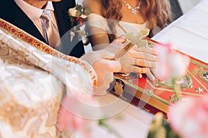 Priest holding cross on groom and bride hand on bible at altar i