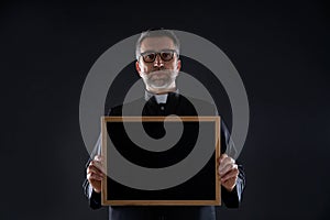 Priest holding empty blackboard copy space