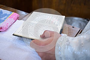 The priest holds the Bible at the altar, church utensil, the Bible on the table, ceremony of water baptism christening