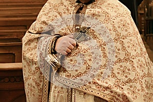 The priest holds the cross and conducts the rite of baptism