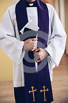 A priest holds an envelope with money in the holy bible during a pastoral visit.