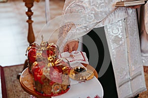 Priest holds two golden rings against background of wedding crowns during Wedding ceremony in Orthodox Ukrainian church