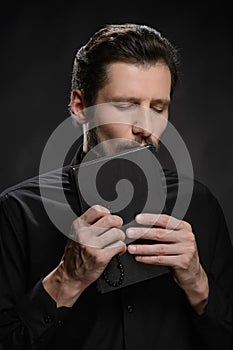 Priest kissing the Holy Bible. Portrait of priest kissing the Ho