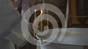 Priest lights candles before baptism ceremony. Font for christening in Church.