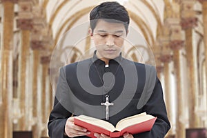 Priest Looking Down at Bible in a Church
