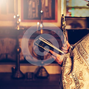 Priest praying in the church holding holly bible and cross