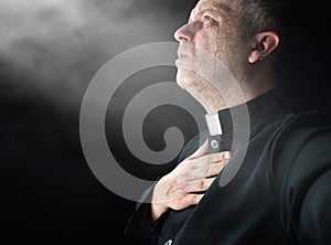 Priest prays silently in a dark room photo