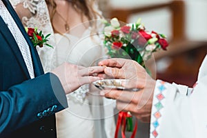 Exchanging wedding rings. priest putting on golden wedding rings on fingers bride and groom in church at wedding matrimony