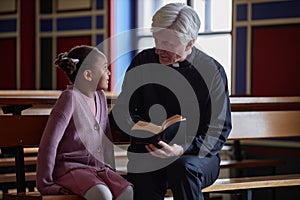Priest reading Bible to little girl