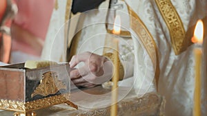 The priest reciting the prayer from bible, two holy candles on foreground