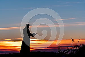 Priest silhoute reading in the sunset light, Romania