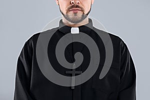 Priest wearing cassock with clerical collar on grey, closeup photo
