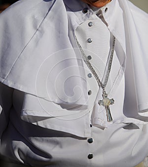 priest with white cassock and silver cross