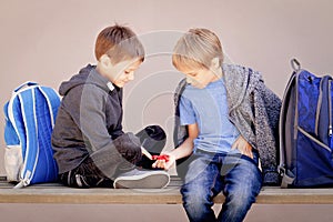 Primary education, school, friendship concept - two boys with backpacks sitting, talking and playing with spinner