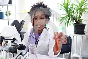 Primary school African curly hair girl does chemistry science experiment in laboratory, cute scientist kid holds chemical test photo