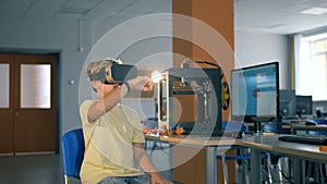 Primary school boy uses virtual reality glasses during computer science class.