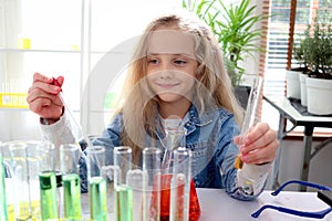 Primary school girl with long blonde hair doing chemistry science experiment in laboratory, cute scientist kid with colorful test photo