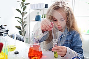 Primary school girl with long blonde hair doing chemistry science experiment in laboratory, cute scientist kid with colorful test photo