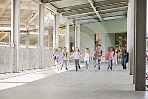 Primary school kids run holding hands in school corridor