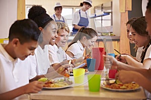 Primary school kids at a table in school cafeteria, close up