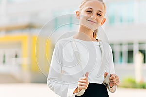 Primary school student, girl with a backpack near the building outdoors, Start of lessons, The first day of autumn