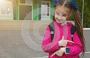 Primary school student. Little girl with a backpack near the building outdoors. Beginning of lessons. First day of autumn