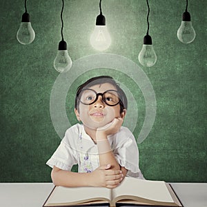 Primary school student sits under light bulb