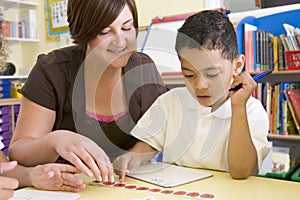 Primary school teacher helping boy learn numbers