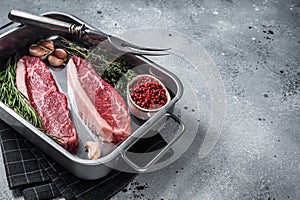 Prime Raw top sirloin beef or cap rump steak in tray with herbs. Gray background. Top view. Copy space