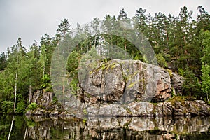 Primeval rock on the shore of a calm lake