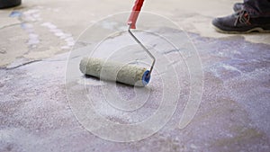 Priming the concrete floor with a roller. Professional floor primer. Leveling concrete floors. Floor repair using a primer