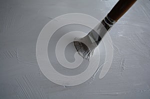 Priming of a wooden panel for painting with white acrylic primer using a bristle brush