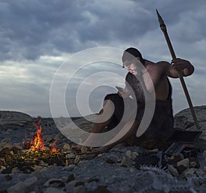 Primitive man siting on the stone with smartphone concept photo