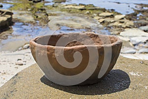 Primitive pottery bowl outside on rocky beach