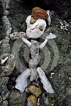 Primitive sculpture of man made of rock, coral and coconuts