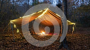 Primitive Tarp Shelter with campfire and fairy lights. Survival Bushcraft setup in the Blue Ridge Mountains near Asheville. During photo